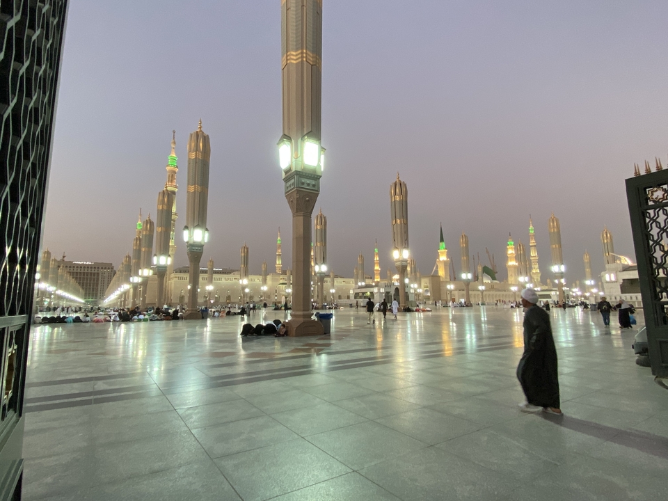 Une magnifique cour de mosquée avec de hauts minarets et des gens.