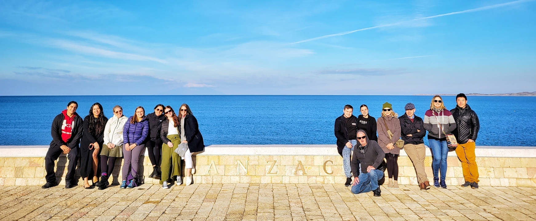 Groupe de personnes posant sur une promenade en bord de mer.