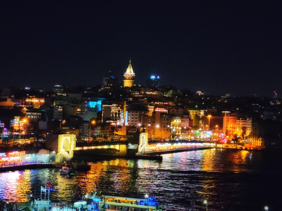 Paysage urbain de nuit avec bâtiments illuminés et reflets.