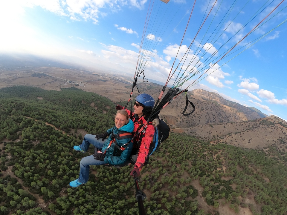 Deux personnes faisant du parapente au-dessus d'une zone boisée.