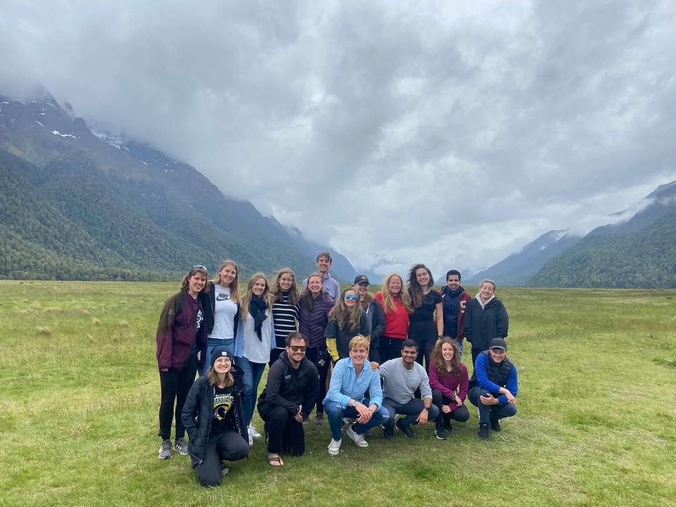 Group of people posing in front of a mountainous landscape.