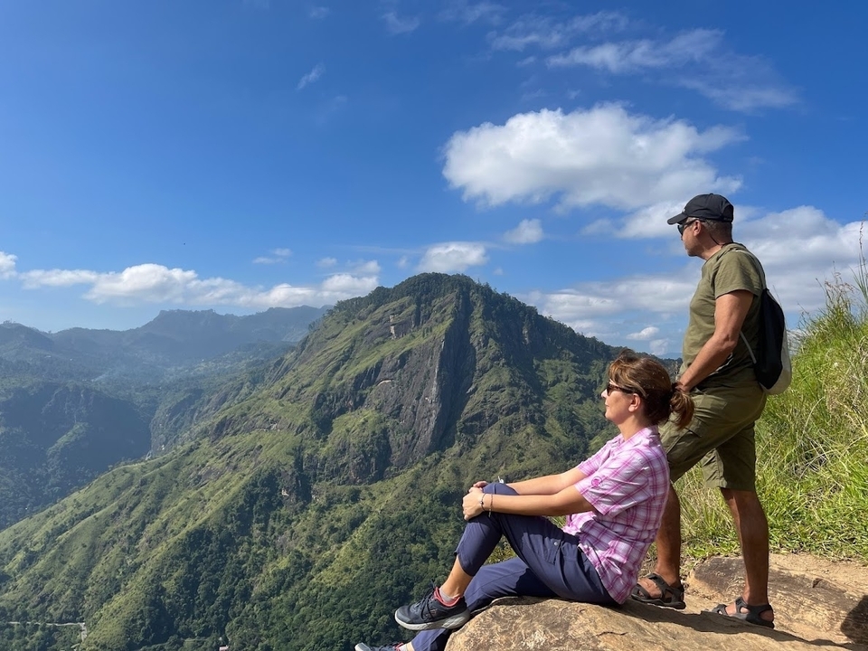 Deux personnes profitant d'un paysage montagneux sous un ciel bleu dégagé.