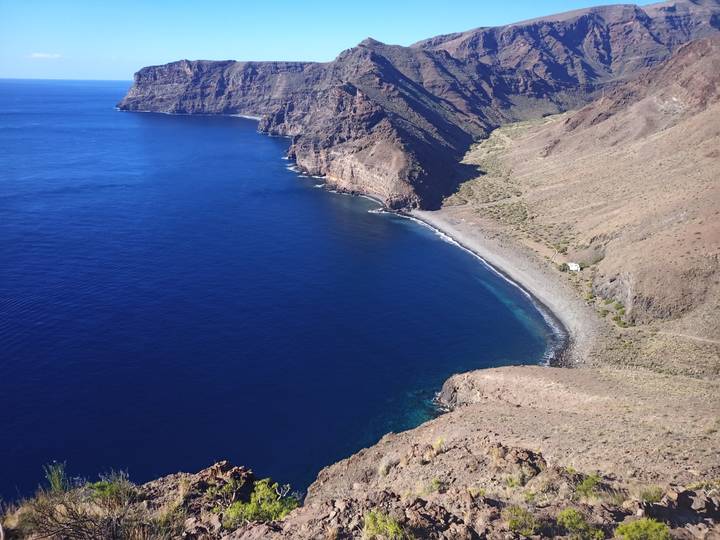 Falaises et une plage isolée adjacente à un océan bleu profond.