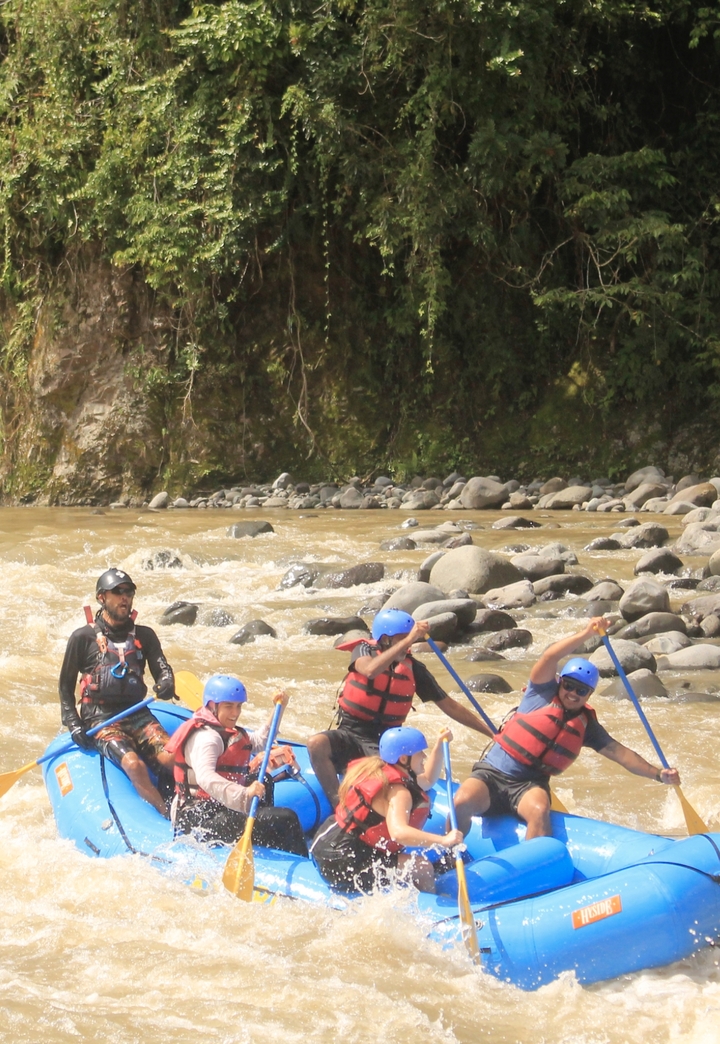 Groupe de personnes faisant du rafting en eaux vives sur une rivière rocheuse.