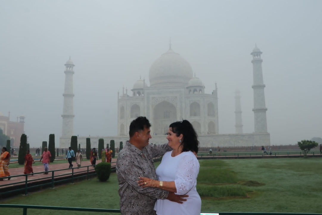 Couple posing in front of the Taj Mahal on a foggy day.
