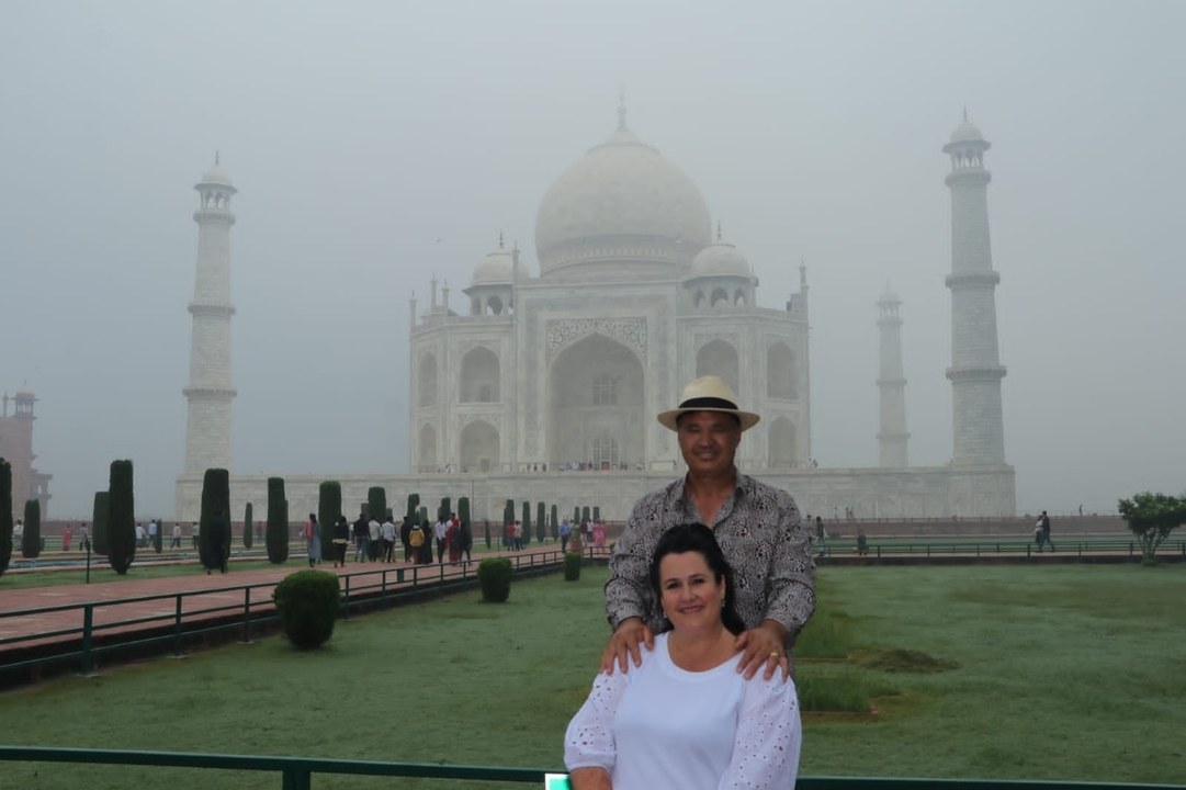 Couple posing with the Taj Mahal as a backdrop on a misty morning.