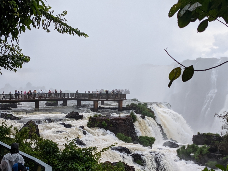 Des touristes sur un pont surplombant de puissantes chutes d'eau.