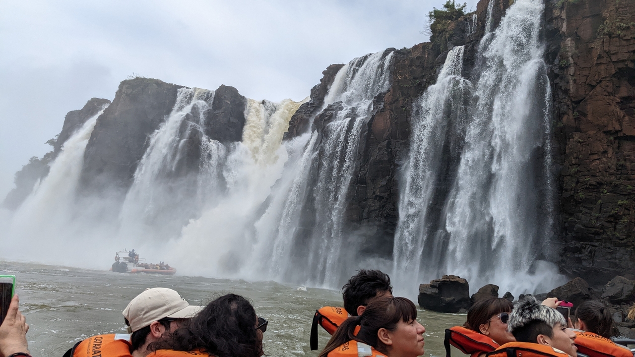 Des touristes sur un bateau près de grandes chutes d'eau.