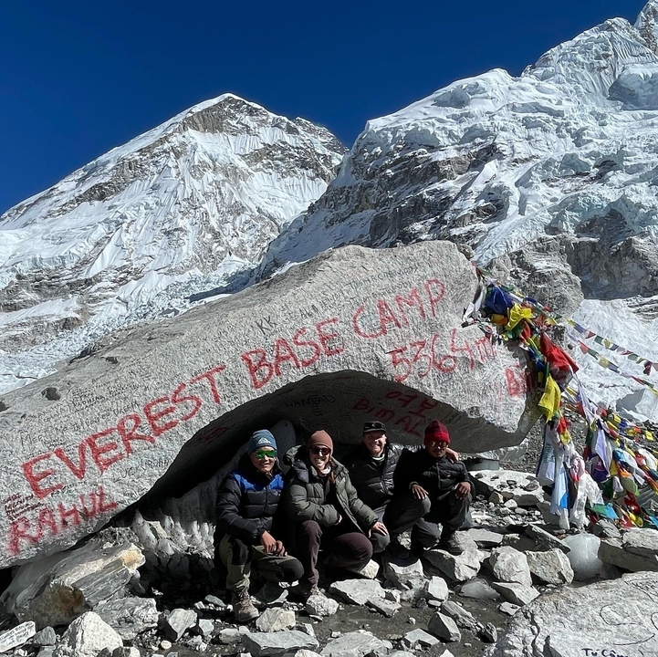 Groupe de personnes posant au camp de base de l'Everest avec les montagnes en arrière-plan.