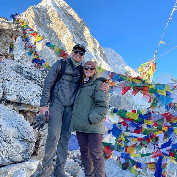 Couple posant avec des drapeaux de prière et des montagnes à l'Everest.