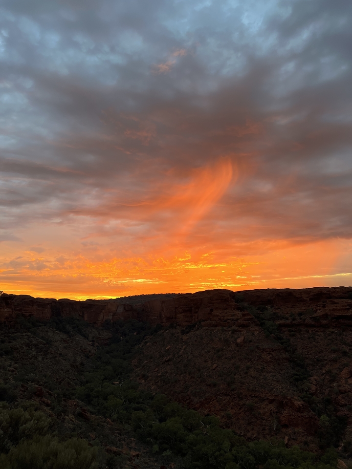 Coucher de soleil éclatant avec des nuages colorés au-dessus d'un canyon.