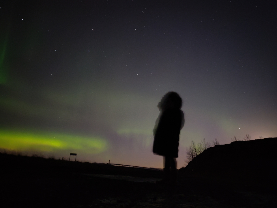 Silhouette d'une personne regardant les aurores boréales.