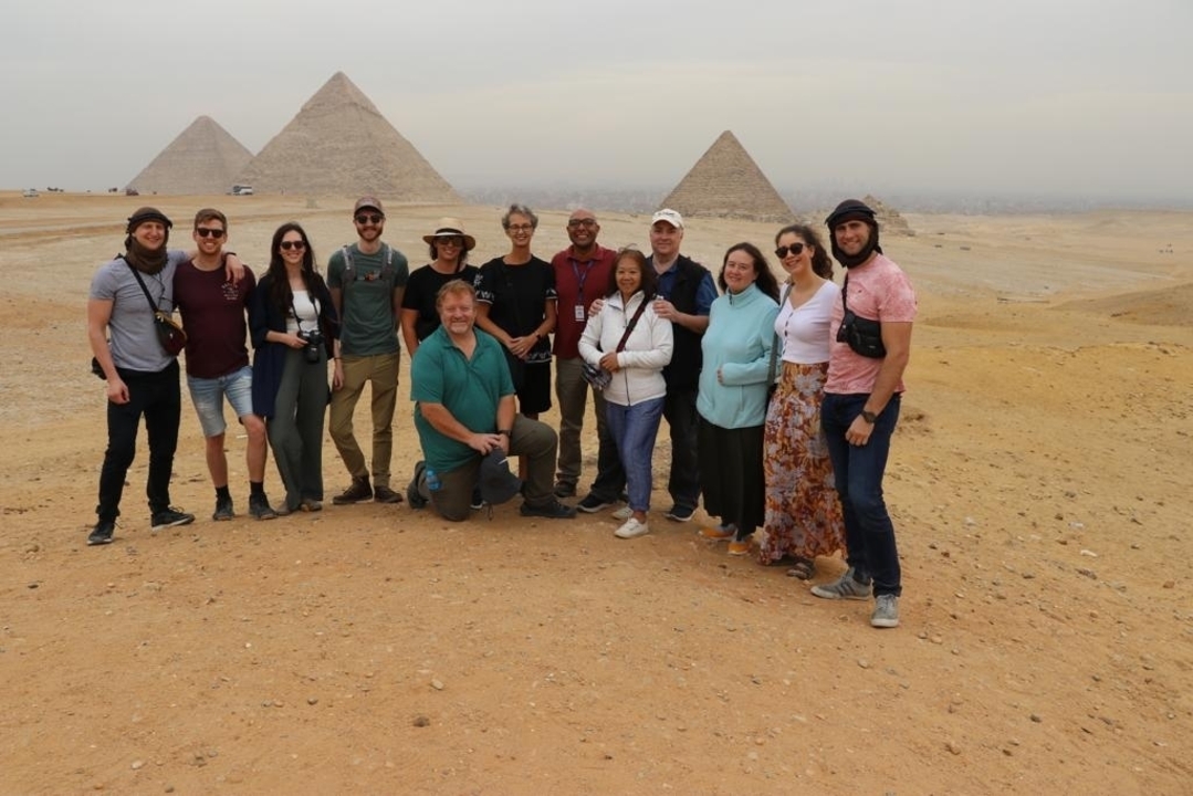 Groupe de touristes avec les pyramides en arrière-plan.