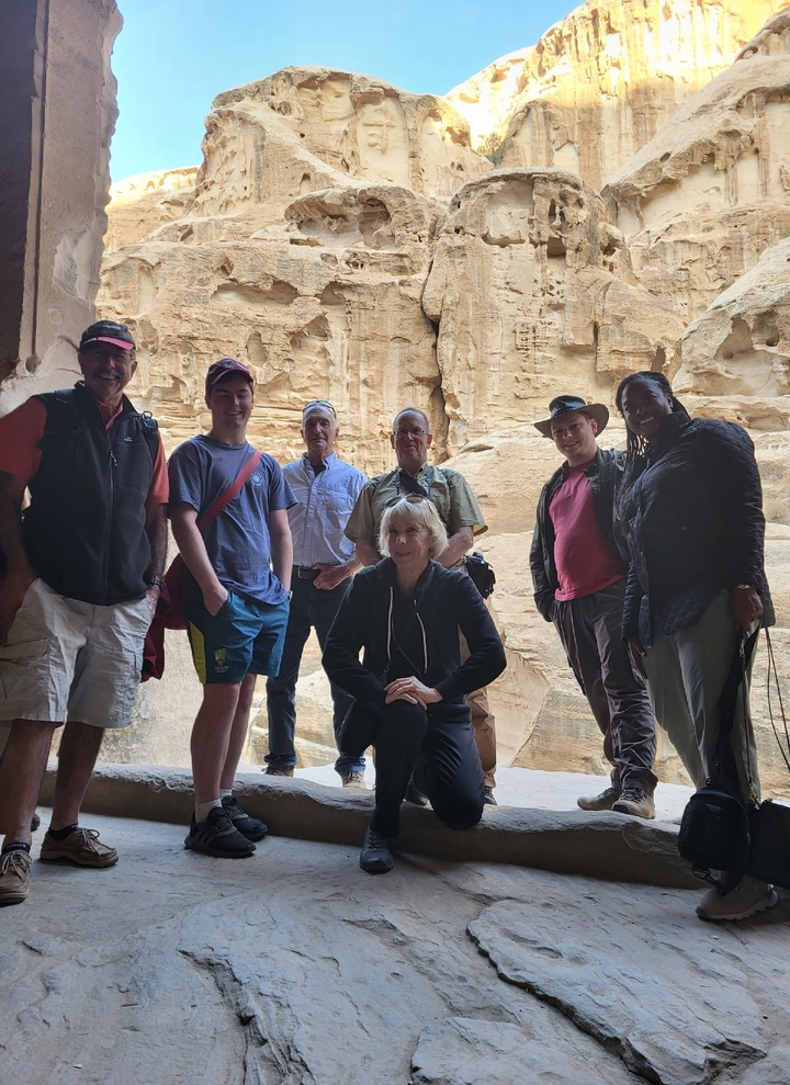 Groupe de personnes posant à l'intérieur d'une structure antique taillée dans la roche à Pétra.