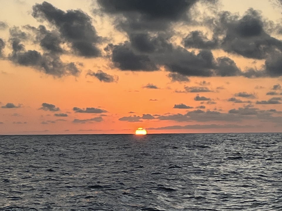 Coucher de soleil sur l'océan avec des nuages dans le ciel.