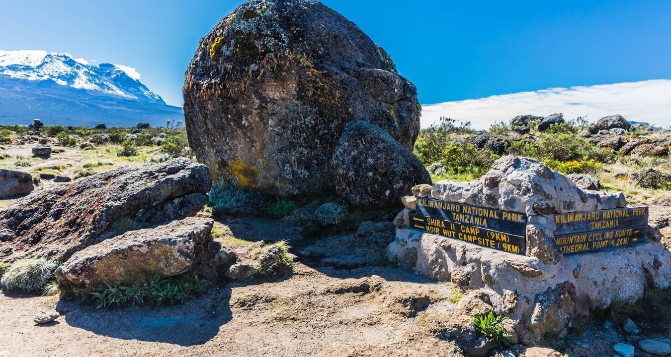 Gran roca y señal de dirección en el Parque Nacional del Kilimanjaro.