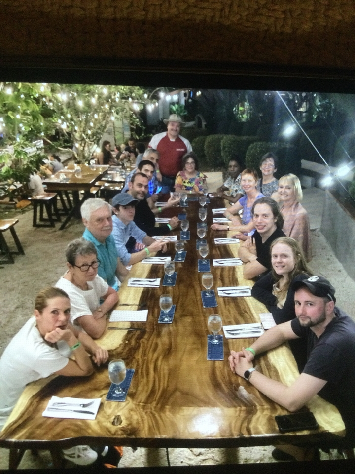 Grand groupe de personnes assises à une table de dîner en plein air.