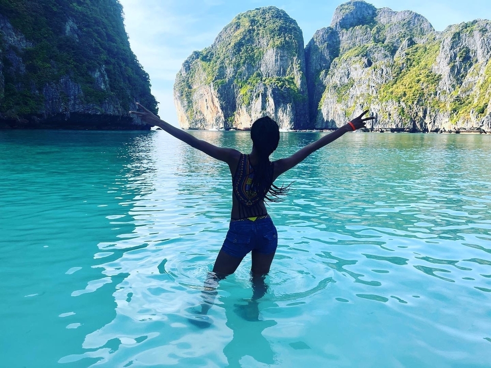 Personne debout dans l'eau avec les bras levés et des falaises pittoresques