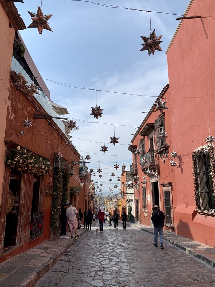 Rue avec des décorations d'étoiles suspendues et des bâtiments coloniaux.