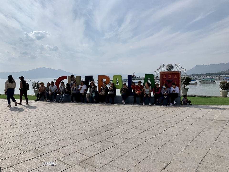 Groupe de personnes assises au bord d'un lac avec un panneau coloré.