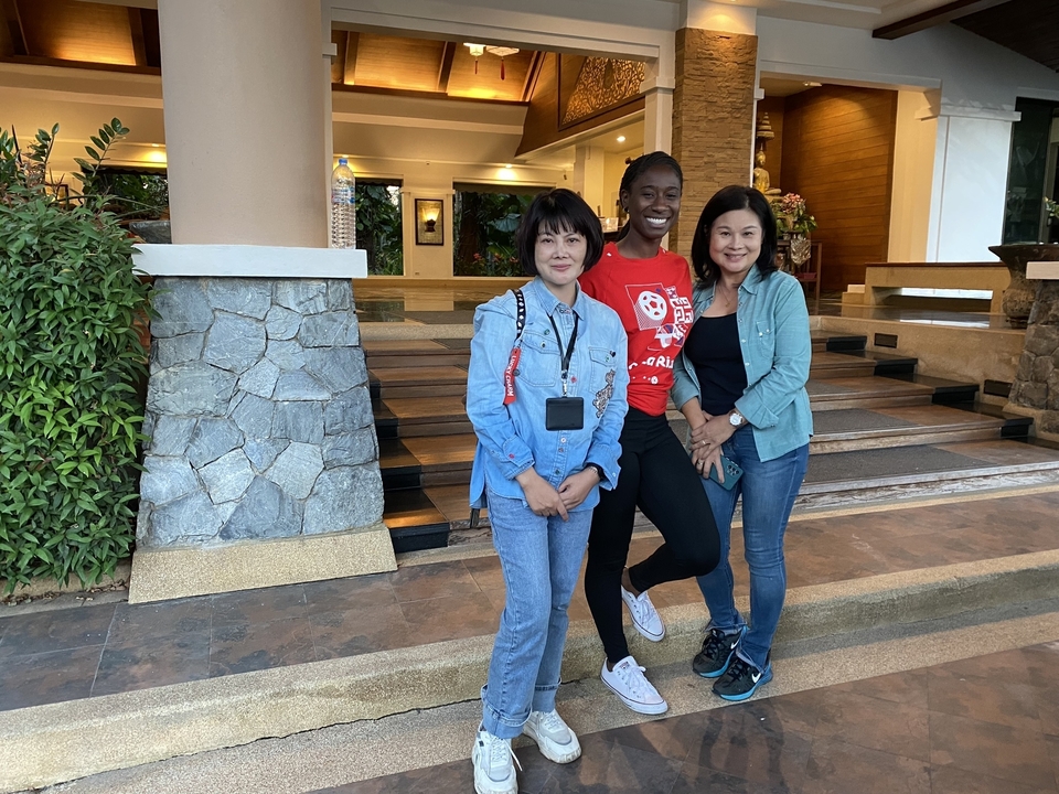 Trois femmes posant ensemble devant un bâtiment.