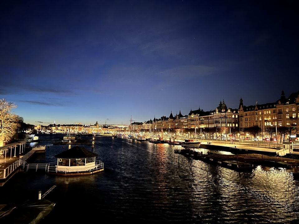 Vue nocturne d'un canal urbain avec les lumières se reflétant sur l'eau.