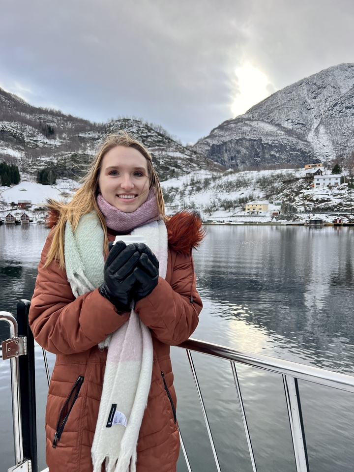 Personne avec une tasse devant un paysage enneigé.