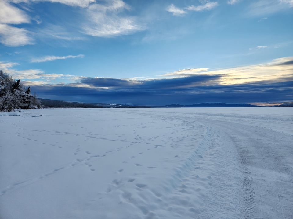 Paysage enneigé avec une route menant vers des montagnes lointaines couvertes de neige.