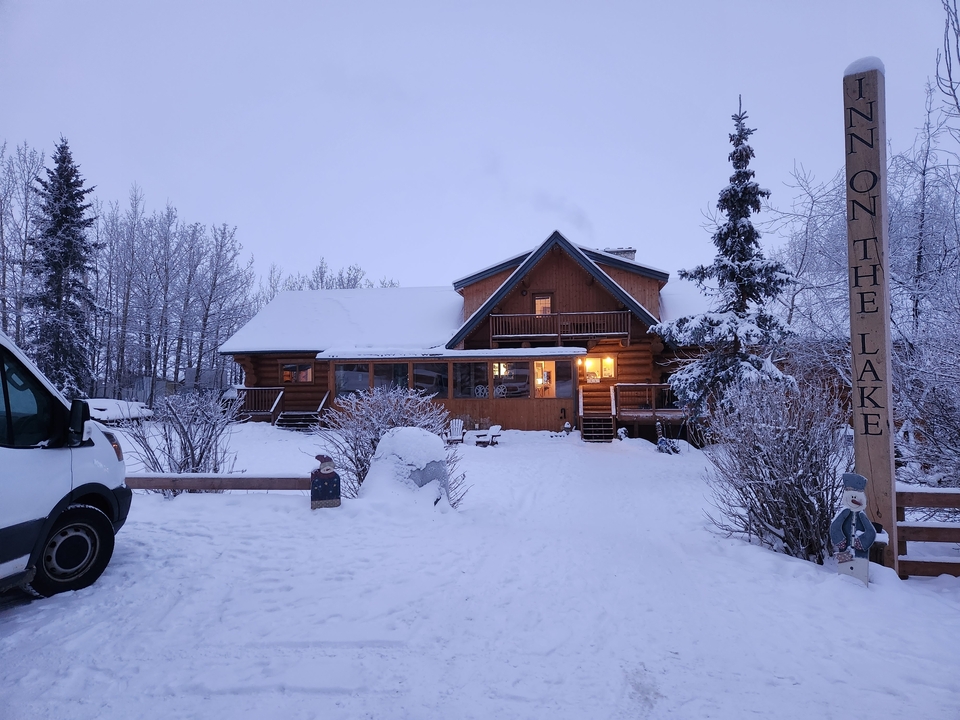 Une cabane d'aspect douillet recouverte de neige pendant la soirée.