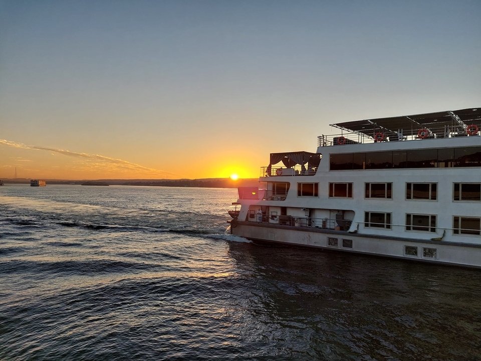 Bateau de croisière naviguant au coucher du soleil sur le Nil.