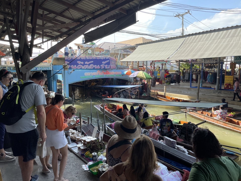 Des gens regardant un marché flottant avec de la nourriture et des produits.