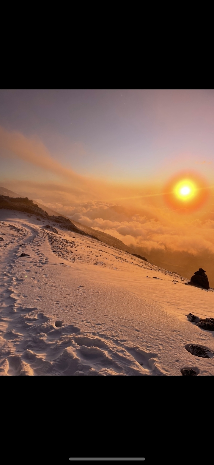 Sentier de montagne avec marches dans la neige au coucher du soleil.