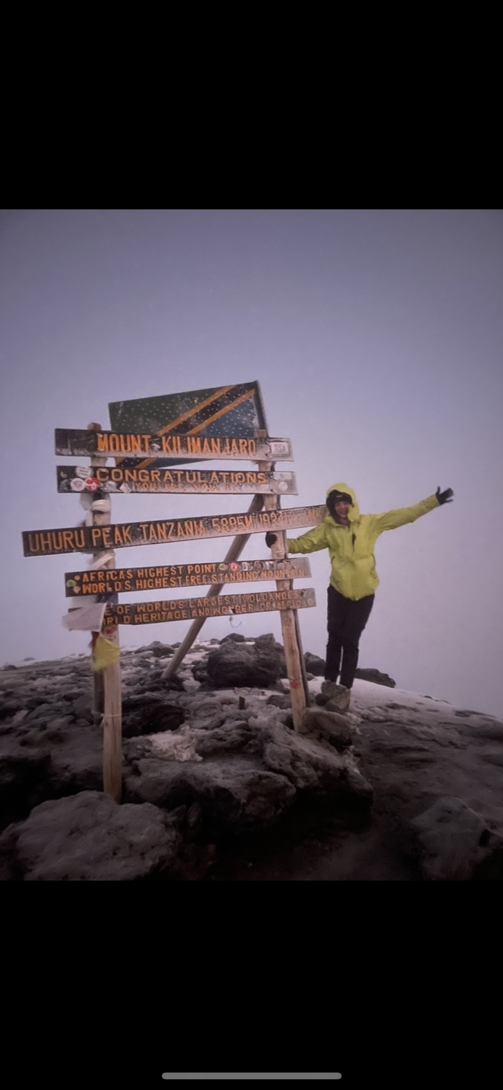 Personne qui pose devant le panneau du pic Uhuru au sommet.