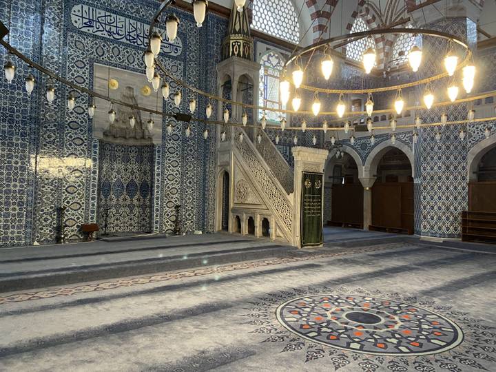 Intérieur magnifiquement carrelé d'une mosquée, avec des luminaires.
