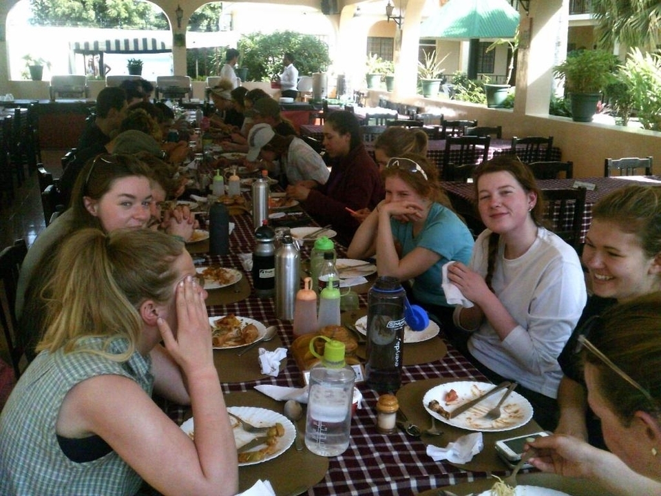 Groupe de personnes mangeant ensemble à une longue table dans un restaurant.