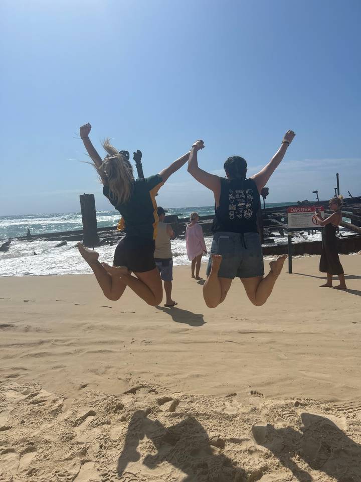 Des gens qui sautent sur une plage de sable.