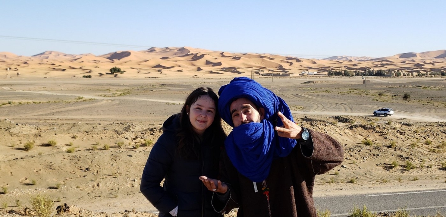 Zwei Menschen in traditioneller Kleidung in einer Wüstenumgebung.