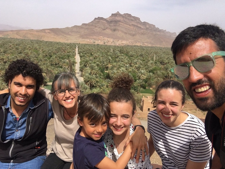Gruppe von sechs Personen, die in einem üppigen Garten lächeln.