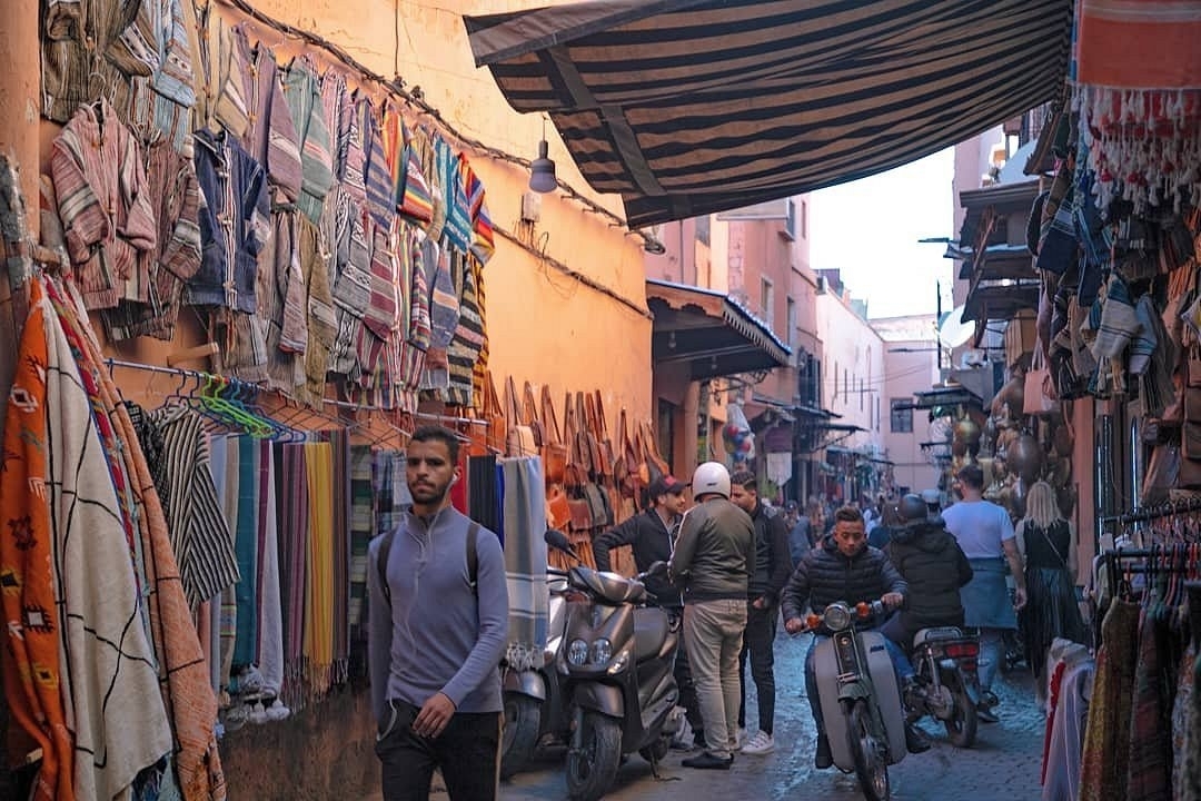 Menschen gehen durch einen belebten Markt mit Textilien.
