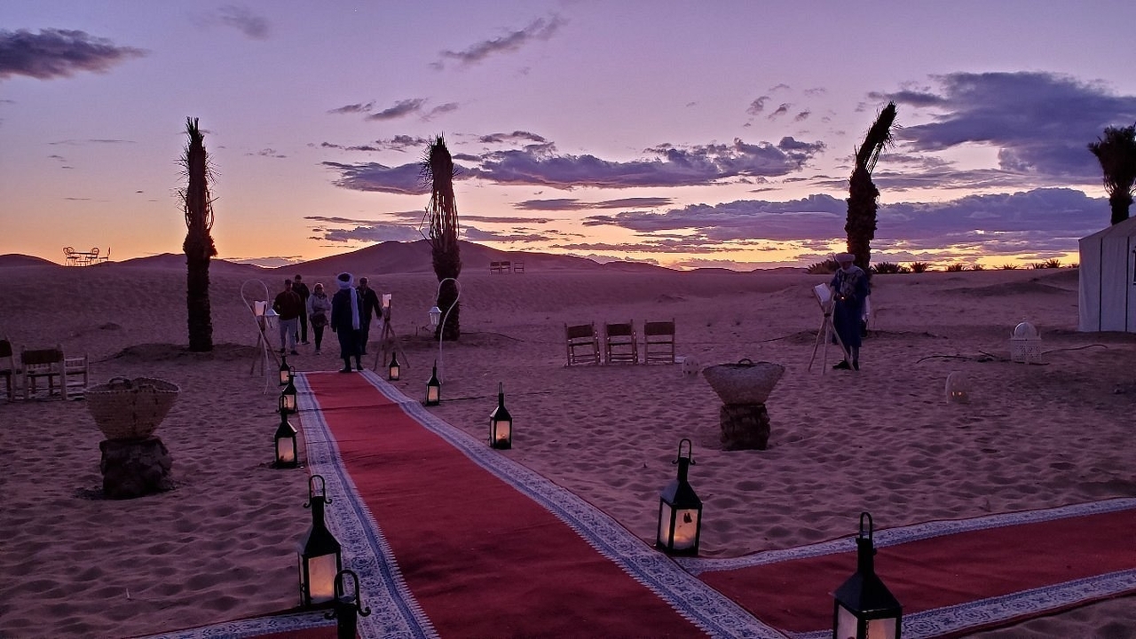 Sonnenuntergang über einer Wüste mit einem mit Teppich ausgelegten Gehweg, der in die Ferne führt.