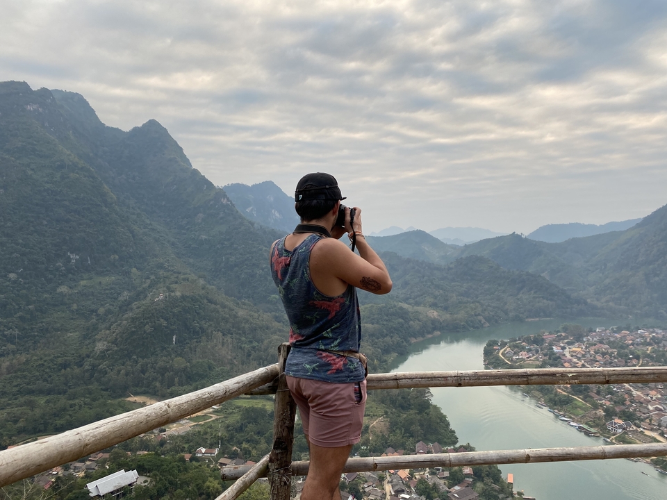 Person taking photos of a scenic hilly landscape with a river.