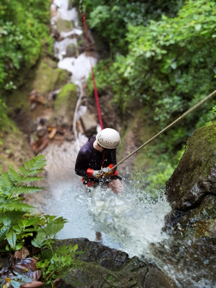 Personne qui fait de la descente en rappel le long d'une cascade.