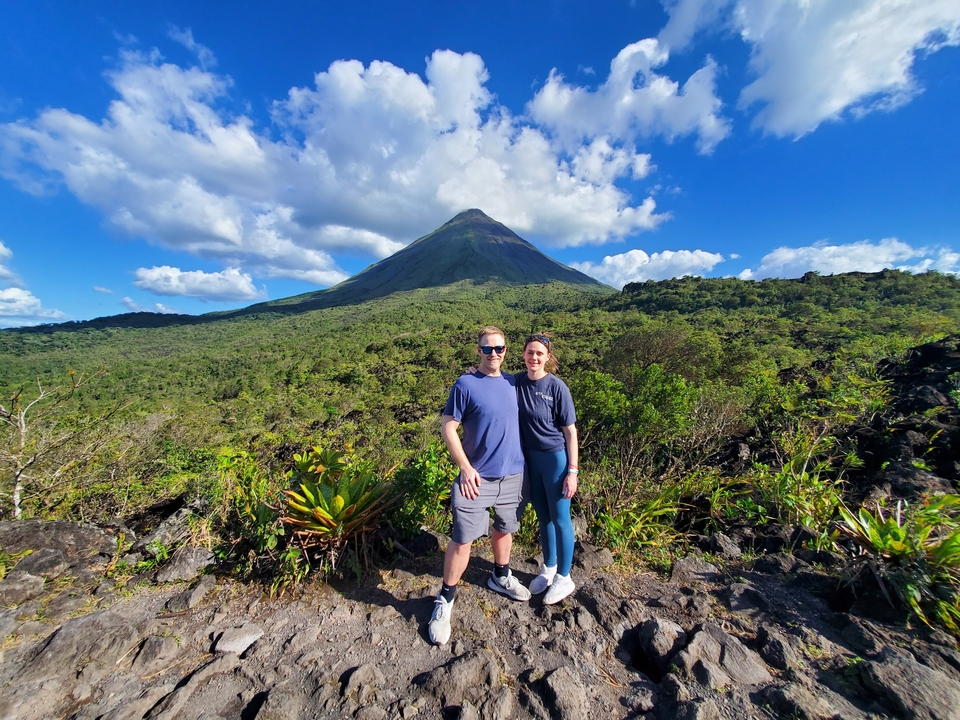 Deux personnes posant avec le volcan Arenal en arrière-plan.