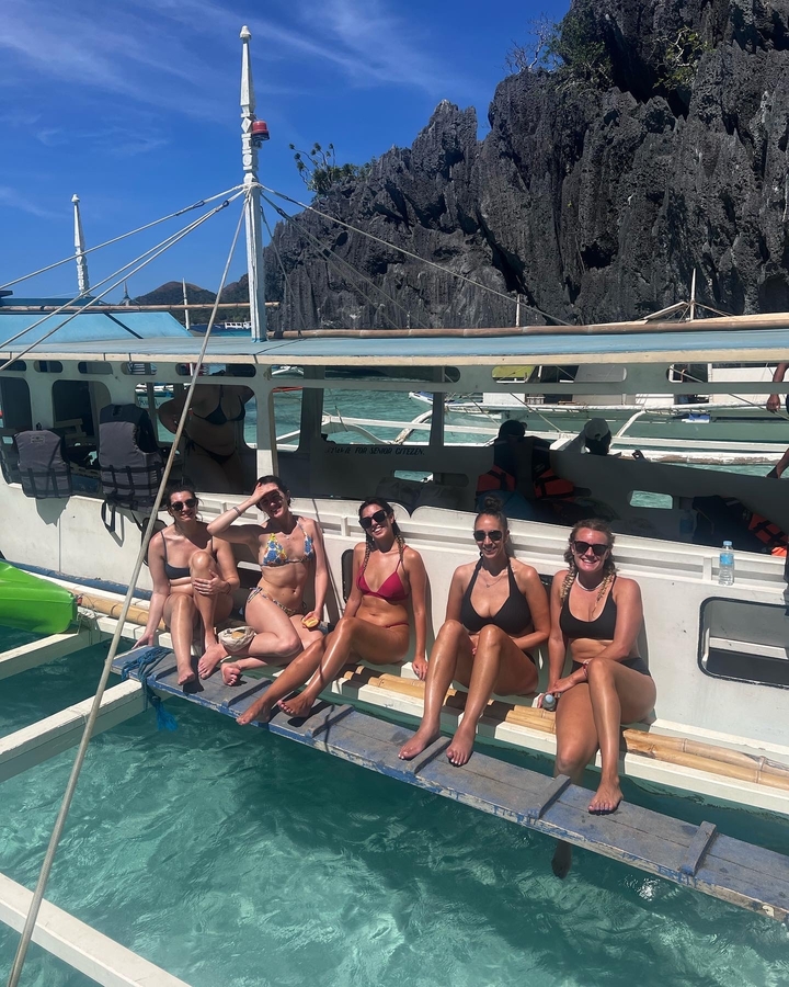 A group of friends sitting on a boat in sunny, clear weather.