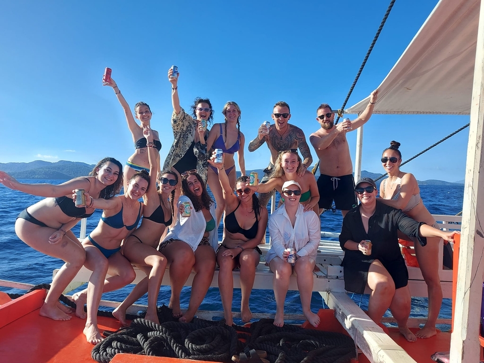 A group of people enjoying a boat ride, smiling and holding drinks.
