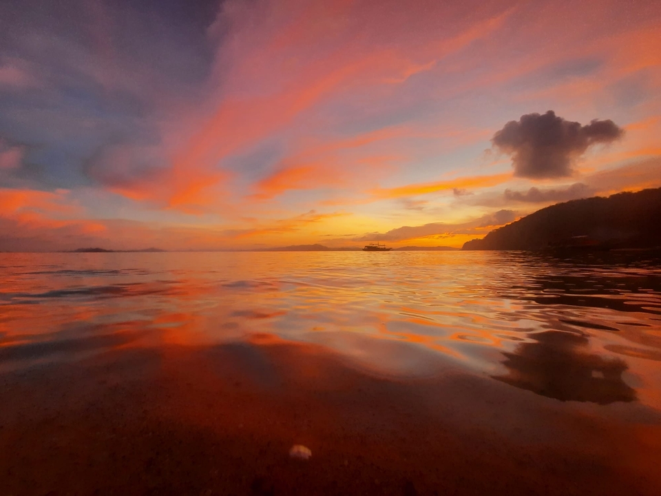 A vibrant sunset over calm waters reflecting pink and orange hues.
