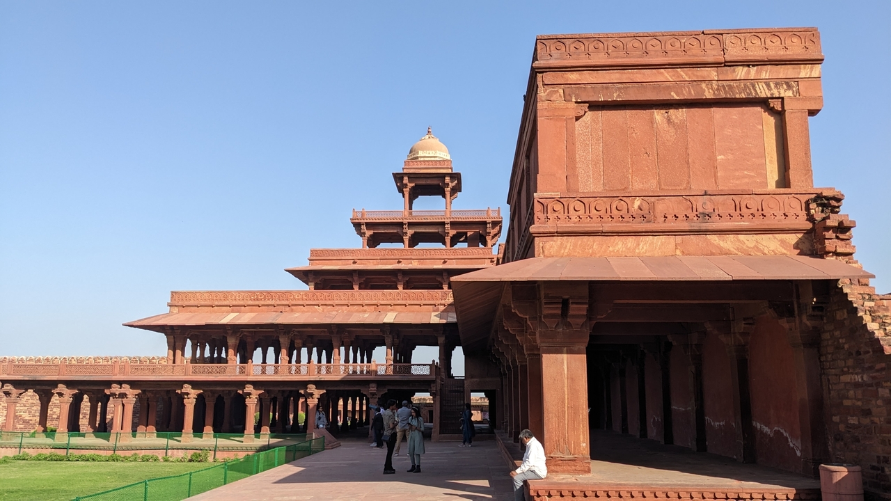 Un bâtiment historique brun-rougeâtre avec plusieurs personnes à proximité.