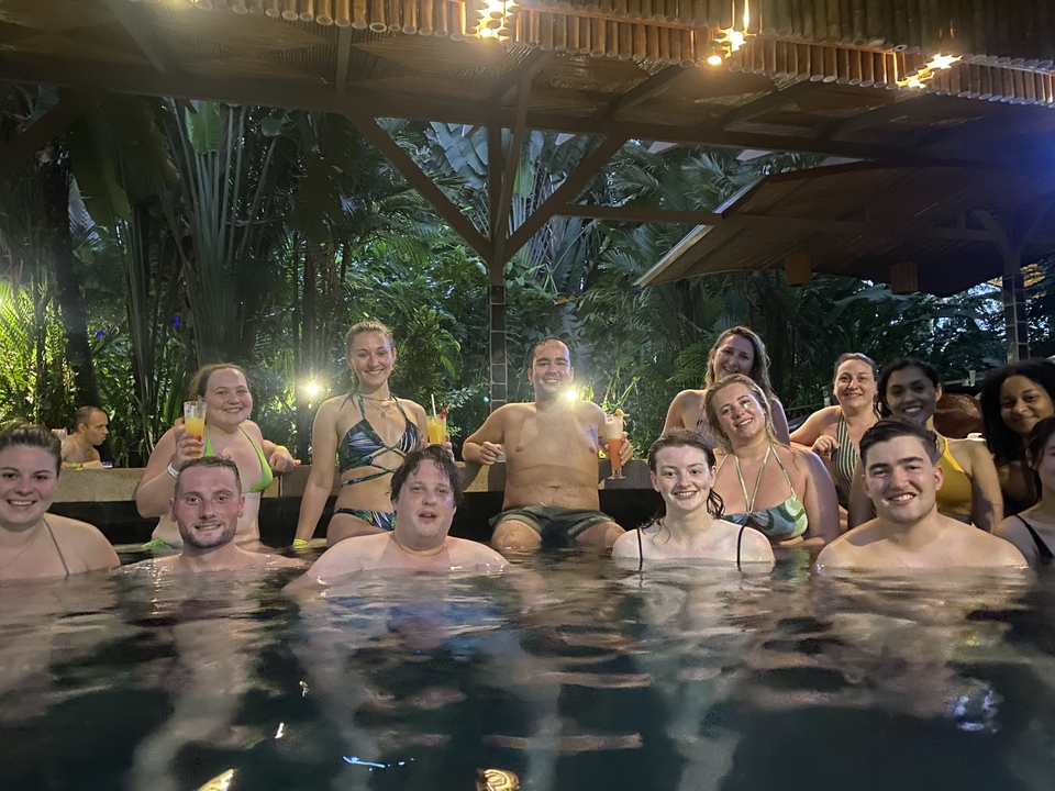 Un groupe de personnes profitant d'un bassin thermal dans un cadre tropical luxuriant.