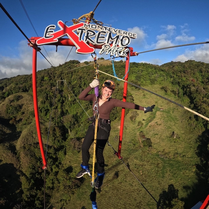 Une personne pratiquant une activité de tyrolienne avec de luxuriantes collines vertes en arrière-plan.