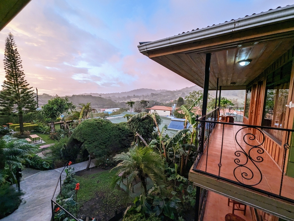 Une vue panoramique depuis une terrasse surplombant une vallée verdoyante au coucher du soleil.